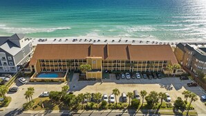 A hotel with a pool, beach view, and parking lot.