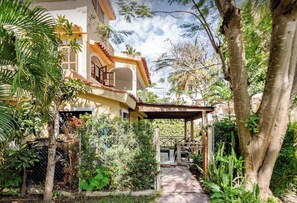 A house with a covered patio, surrounded by lush greenery and a clear sky.
