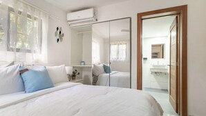 Hotellihuone, jossa on suuri sänky, yöpöytä, peili ja vaatekaappi.