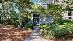 A pathway leading to a building with a modern design, surrounded by lush greenery and trees. - Perfect Location for a Family Vacation! (Hilton Head)