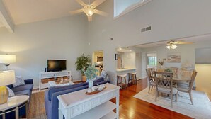 A spacious living area with a sofa, TV, dining table, and ceiling fans. - Perfect Location for a Family Vacation! (Hilton Head)