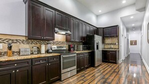 A modern kitchen with dark wood cabinets, stainless steel appliances, and a patterned backsplash.