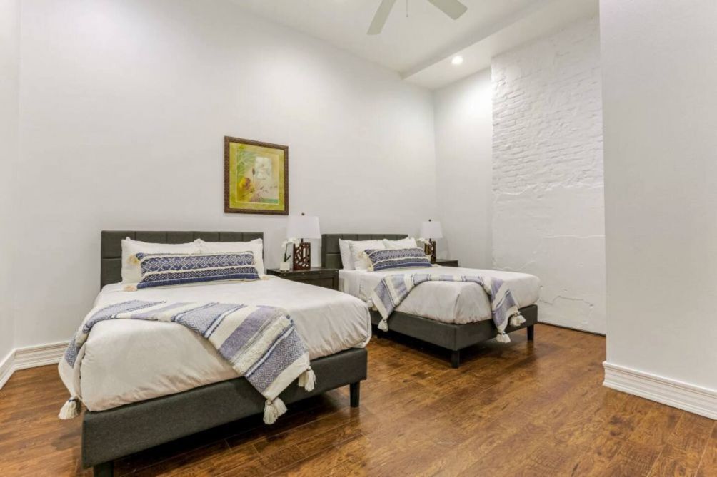 A bedroom with two beds, white walls, and a wooden floor.