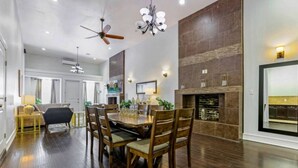A spacious dining area with a wooden table and chairs, a ceiling fan, and a fireplace.