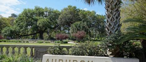 A sign reading "AUDUBON PARK" with a backdrop of lush greenery and trees.