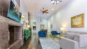 A hotel lobby with a fireplace, blue armchairs, a white sofa, and a large painting on the wall.