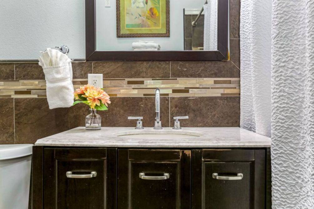 A bathroom with a marble sink, a towel rack, a vase with flowers, and a mirror above the sink.