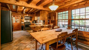 A wooden cabin interior with a kitchen, dining area, and large windows. - Dupont Forest Trailside Cabin (Hendersonville)