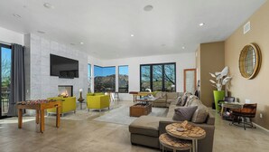 Ein geräumiges Wohnzimmer mit Tischfußball, einer Couch und einem Kamin.