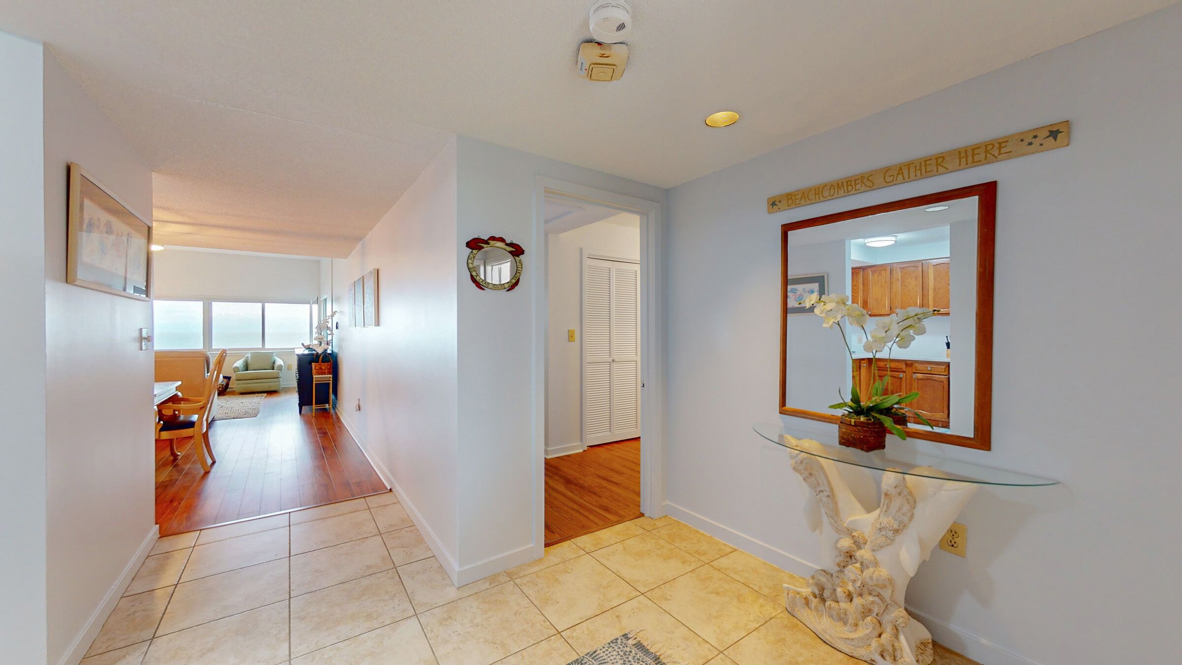 A hallway with a glass console table, a mirror, and a sign above it.