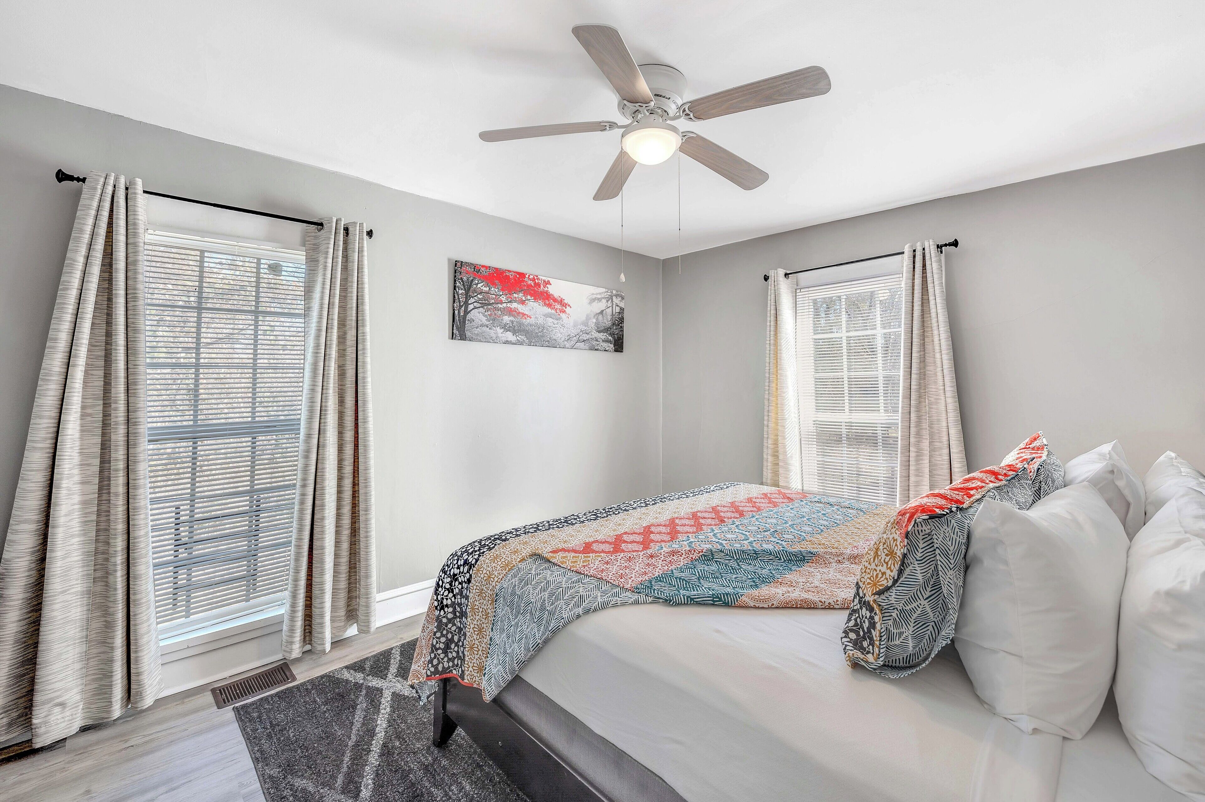 A bedroom with a bed, a ceiling fan, and a window with curtains.