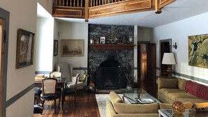 A spacious living room with a stone fireplace, wooden staircase, and comfortable seating areas. - Greystone Manor - An isolated 30 Acres in Stowe,  with Hot Tub!!! (Stowe)