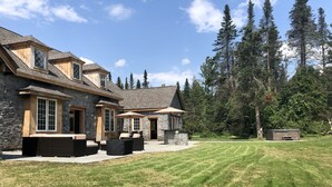 A stone house with a patio area featuring outdoor furniture and umbrellas. - Greystone Manor - An isolated 30 Acres in Stowe,  with Hot Tub!!! (Stowe)
