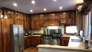 A kitchen with wooden cabinets, stainless steel appliances, and a large island. - Greystone Manor - An isolated 30 Acres in Stowe,  with Hot Tub!!! (Stowe)