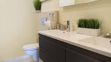 Une salle de bain moderne avec un lavabo blanc, un meuble-lavabo foncé et un grand miroir.