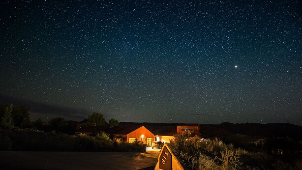 Cielo estrellado con una casa y un cartel que dice "S5" en un entorno rural.