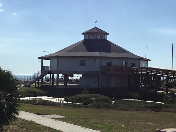 A white building with a central tower, a covered walkway, and a view of the sea.