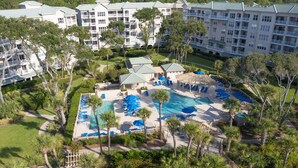 A resort with multiple buildings, a central pool area with sun loungers, and surrounding greenery. - Top floor vacation rental - expansive ocean views and steps from the beach! (Hilton Head)