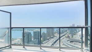 Un apartamento de altura con un balcón grande que ofrece vistas a un paisaje urbano y una masa de agua.