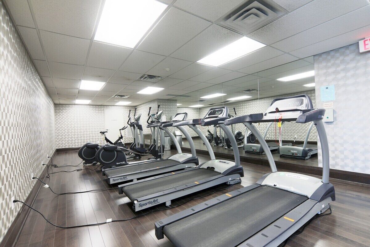 Ein Fitnessstudio mit mehreren Laufbändern, Ergometer und Crosstrainern.