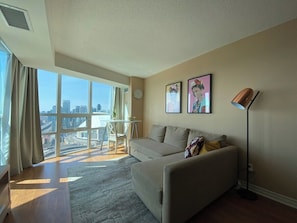A modern living room with a large window, a sofa, a coffee table, and a floor lamp.