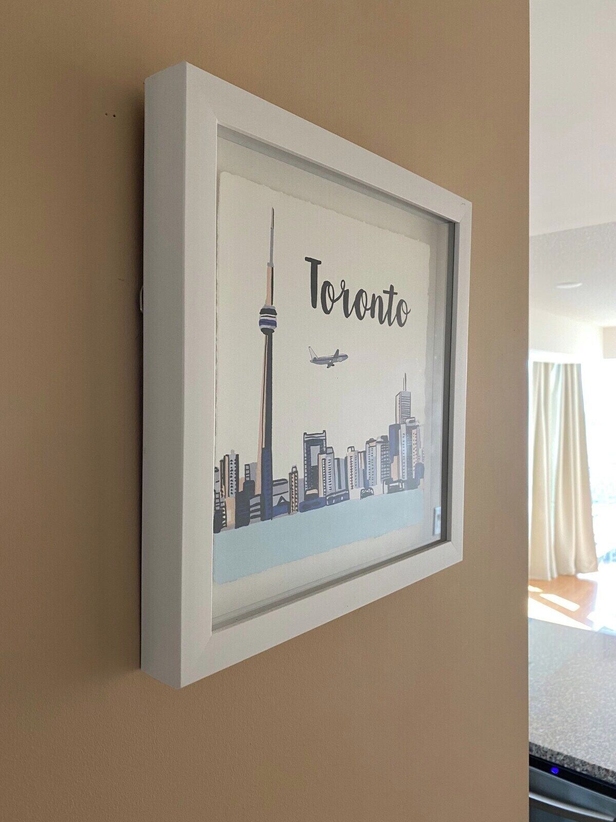 Ein gerahmtes Stadtbild von Toronto mit dem CN Tower und Hochhäusern.