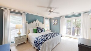 A bedroom with a bed, a nightstand, a ceiling fan, and a window with curtains. - Beach Access Across the Street! (Hilton Head)