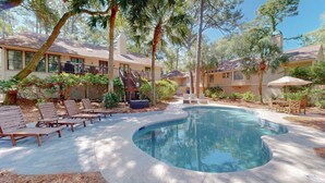 A pool with lounge chairs, a covered seating area, and a building with a balcony. - Beach Access Across the Street! (Hilton Head)