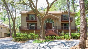 A two-story building with a central archway, balconies on each floor, and a paved driveway. - Beach Access Across the Street! (Hilton Head)