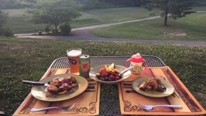 Una mesa al aire libre con platos de comida, una bebida y una lata de refresco.