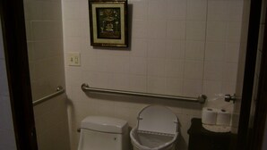Ein kleines Badezimmer mit Toilette, einem Mülleimer und einem gerahmten Bild an der Wand.