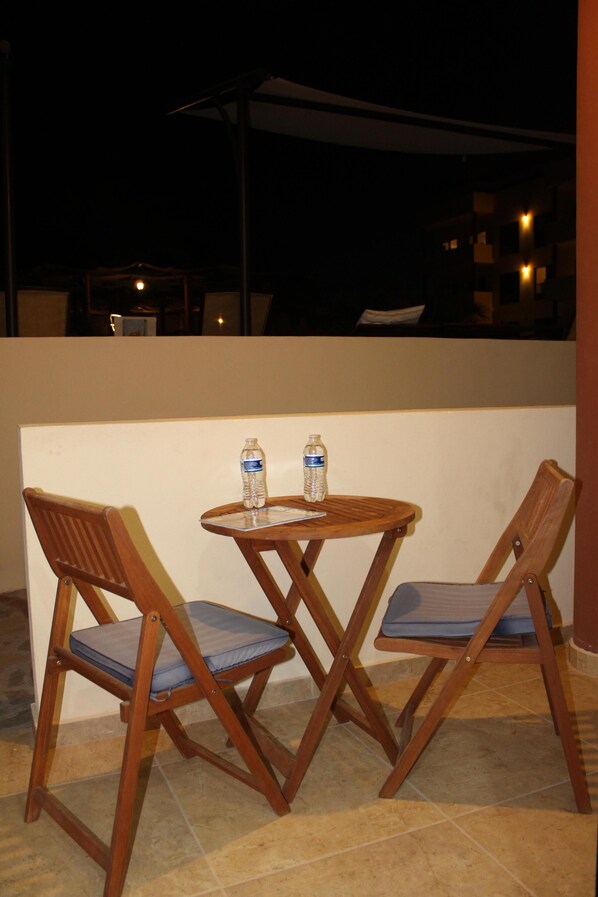 A small outdoor seating area with two wooden chairs and a table, each with a water bottle on it. - Beautiful Studio, Fully Equiped, pool side, Walking Distance To La Ventana Beach (La Ventana)