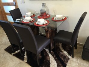 A dining table set with white plates, red placemats, and clear glasses.