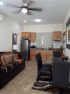 A modern kitchen with wooden cabinets, a stainless steel refrigerator, and a dining area with a glass table and chairs.