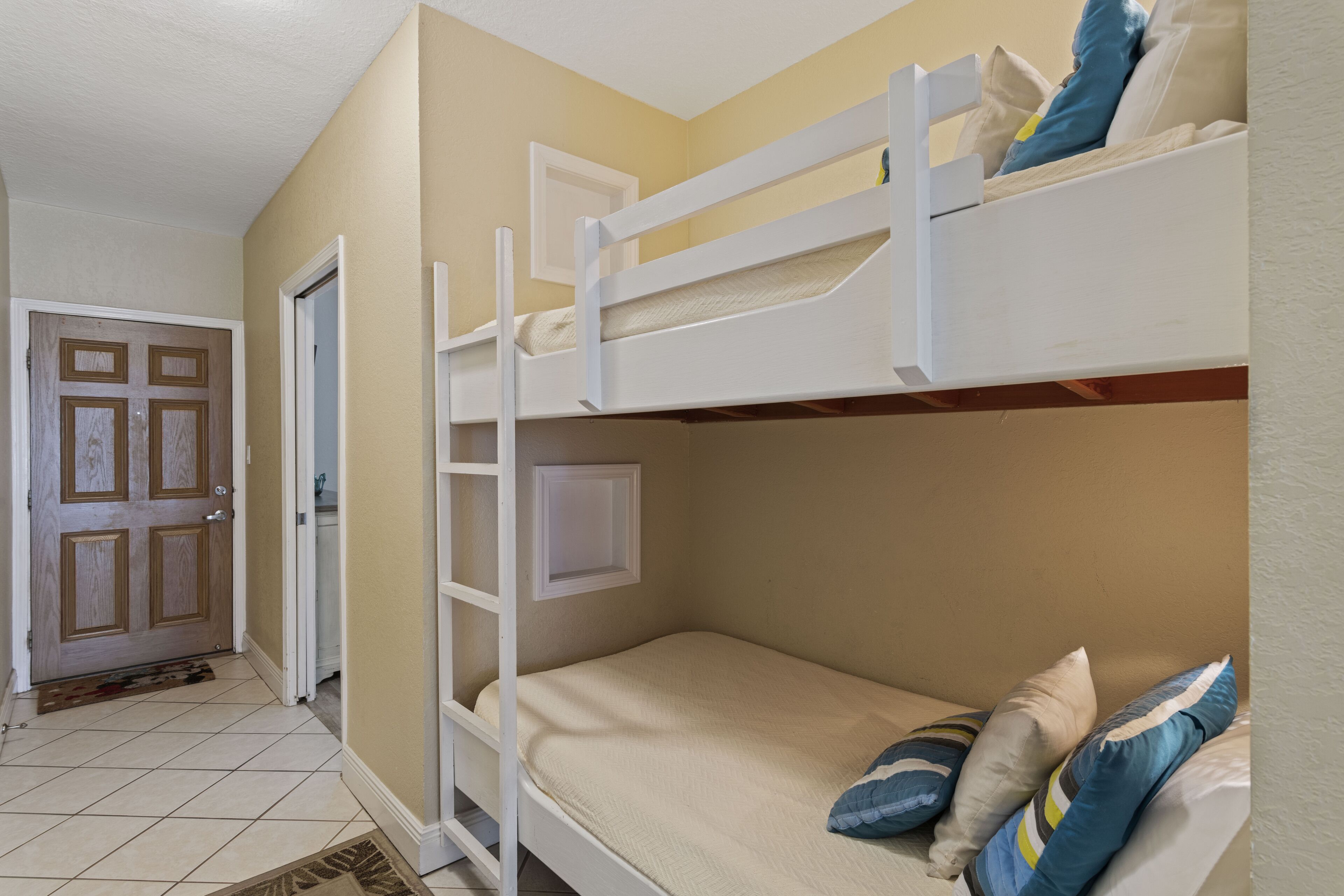 A bunk bed room with a door, a window, and a tiled floor.