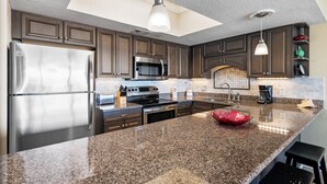 Una cocina moderna con encimeras de granito, electrodomésticos de acero inoxidable y armarios de madera oscura.