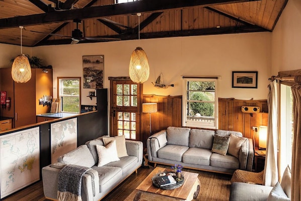 A cozy living room with two sofas, a coffee table, and a wooden ceiling.