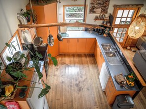 A kitchen with wooden cabinets, a central island, and a hanging pot rack. - Mandala Bruny Island, waterfront, near Restaurant (Alonnah)
