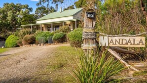 A house with a green roof, a wooden signpost with the name 'MANDALA,' and a gravel driveway. - Mandala Bruny Island, waterfront, near Restaurant (Alonnah)