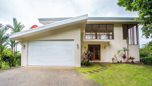 Una casa moderna de dos pisos con garaje, un porche delantero y un césped bien cuidado.