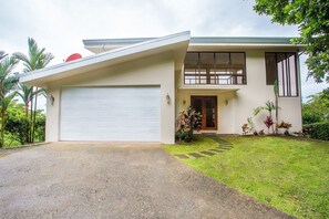 Une maison moderne à deux étages, dotée d’un garage, d’un porche et d’une pelouse bien entretenue.