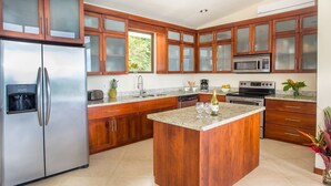 Una cocina con armarios de madera, electrodomésticos de acero inoxidable, encimera de granito y una isla central.