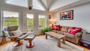 A spacious living room with a large window, a comfortable sofa, a wooden coffee table, and a leather recliner. - In the Estates, close to Owl's Nest, new kitchen, amazing views, minutes off I93 (Thornton)