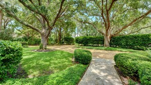 A well-maintained garden with mature trees, manicured lawns, and a stone pathway. - Excellent Cottage Location on Sea Island (Sea Island)