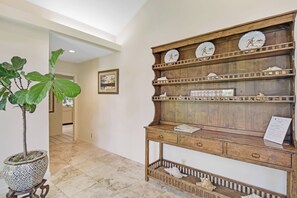 A wooden console table with multiple shelves, a potted plant, and a framed picture.