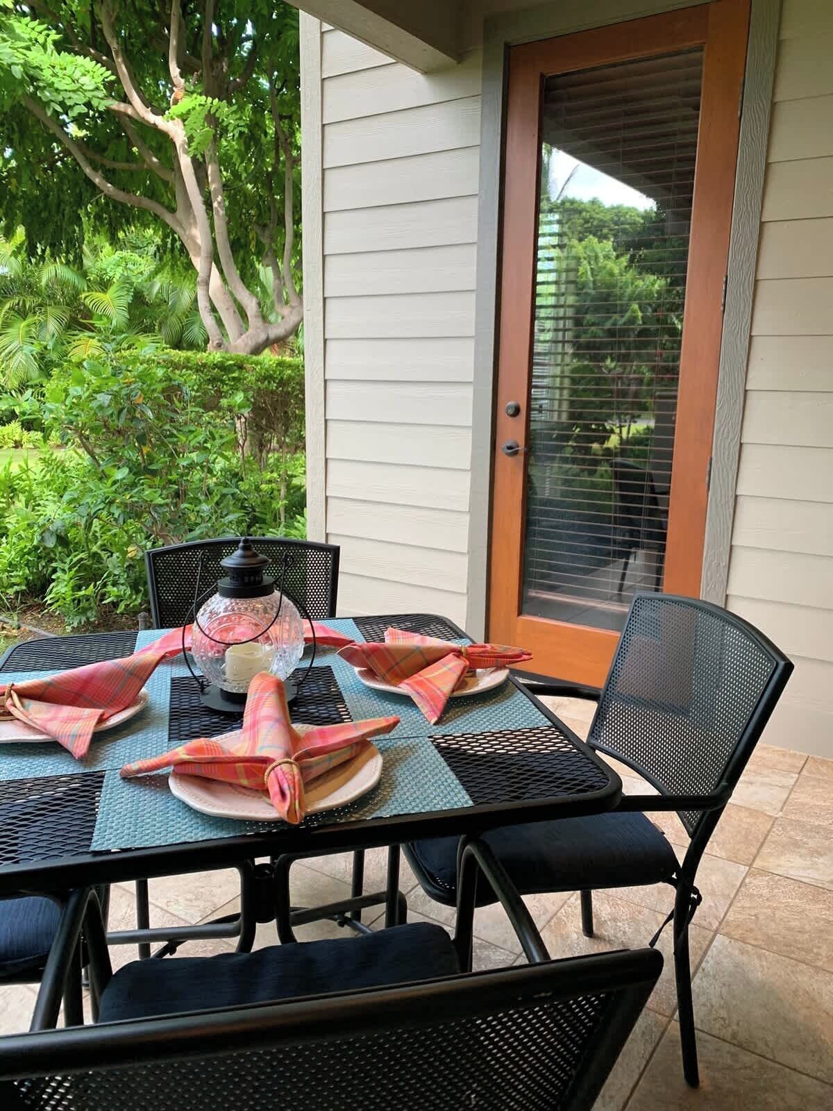 A patio with a table set for four, surrounded by chairs, and a lantern on the table.