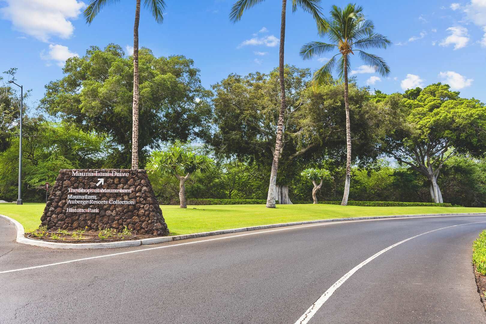 A road sign indicating directions to Mauna Lani Drive, The Shops at Mauna Lani, Mauna Lani Resort, and Historic Park.