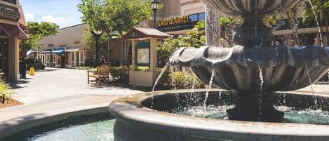 A fountain in a public square with a building labeled "Island Gourmet Markets" in the background.