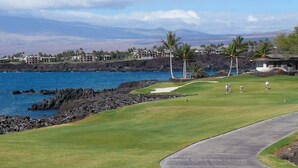 Un campo da golf con vista sull'oceano e sulle montagne sullo sfondo.