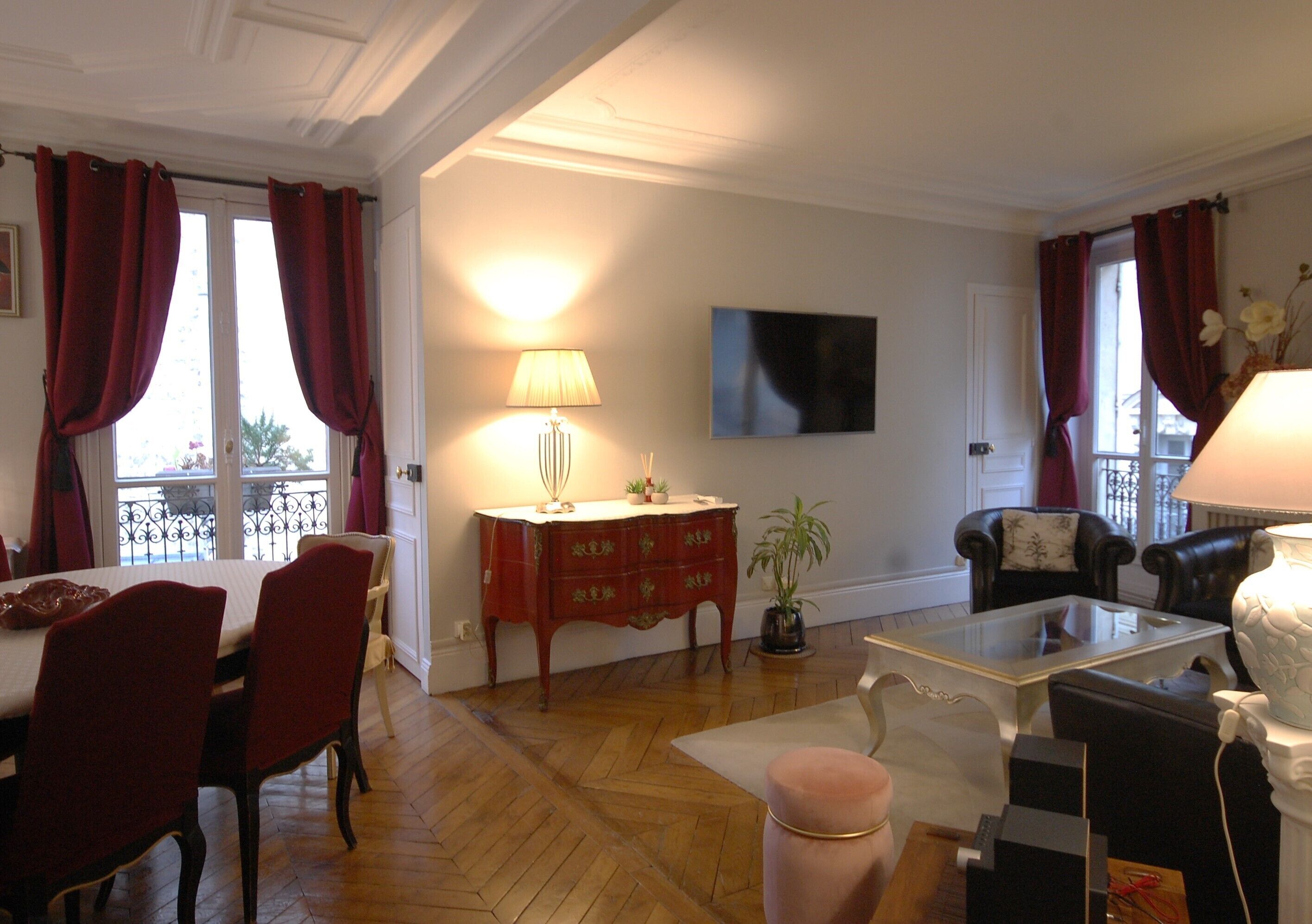 Un salon comprenant un coin repas, un téléviseur fixé au mur et une plante en pot.